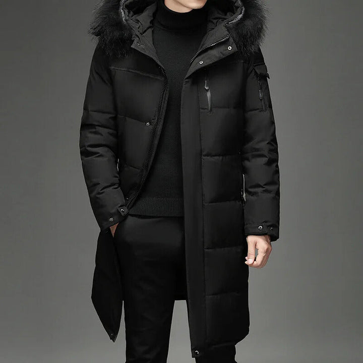 Man wearing black hooded down coat with fur trim, hands in pockets