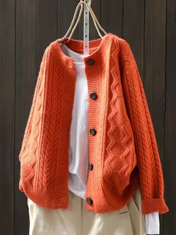 Orange cable knit cardigan on hanger