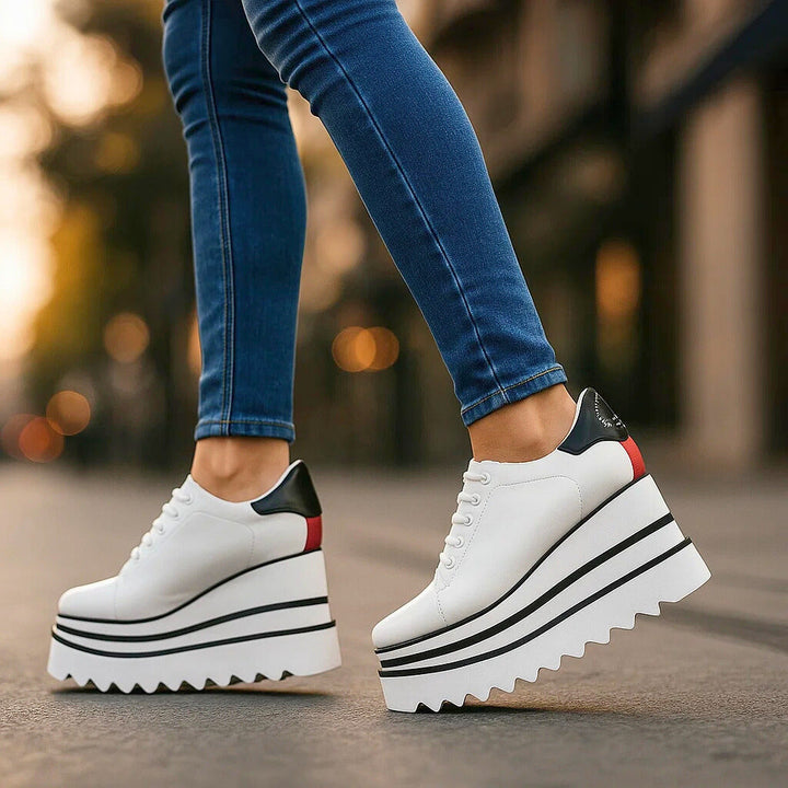White platform lace-up sneakers with contrast red and black heel panel, side profile on model