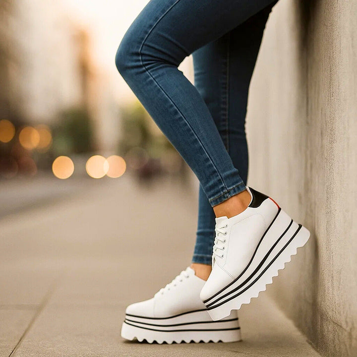 White tiered platform sneakers worn against a wall, side view