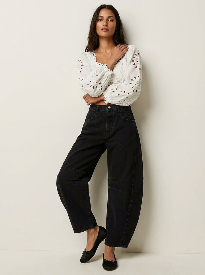 Model wearing black barrel leg denim jeans with eyelet blouse