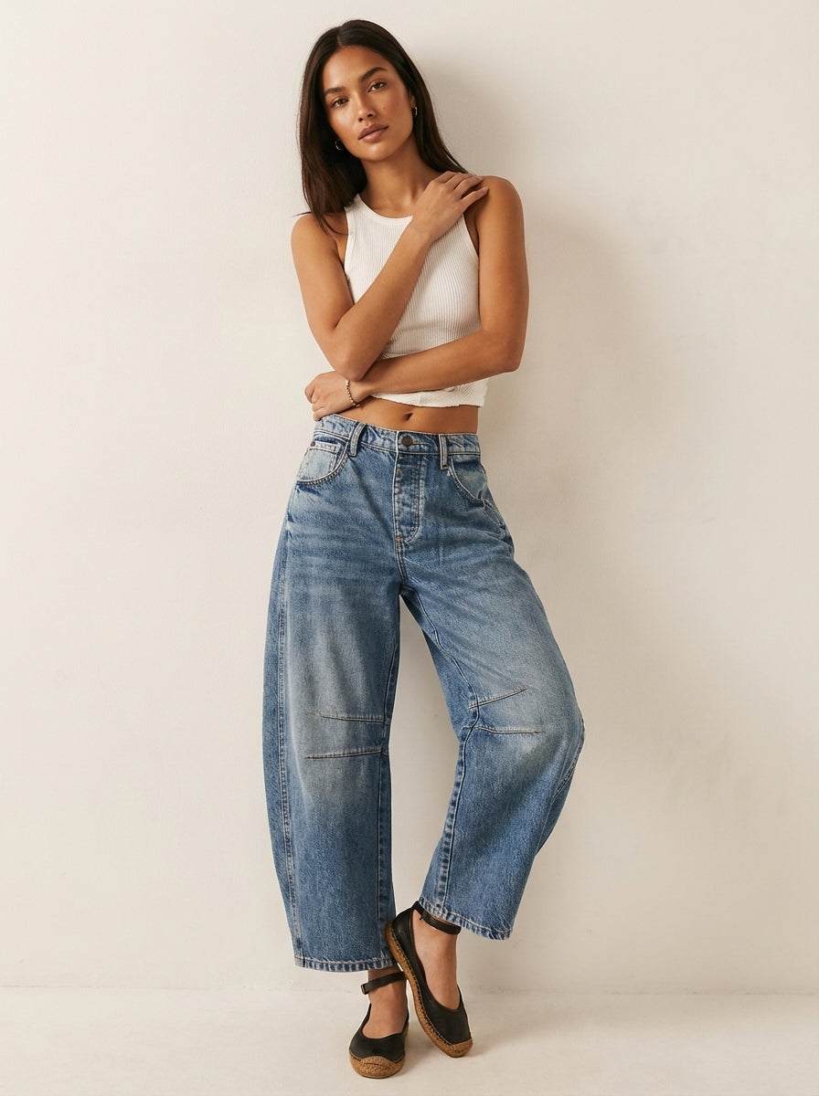 Model wearing medium wash blue barrel leg jeans