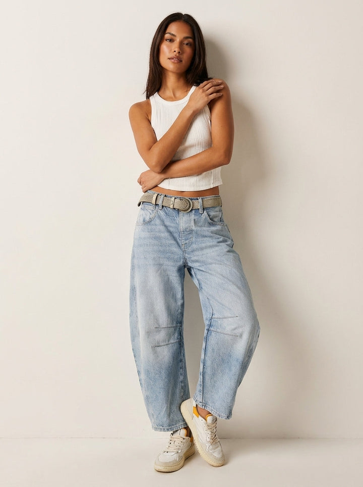 Model wearing light wash blue barrel leg jeans with belt