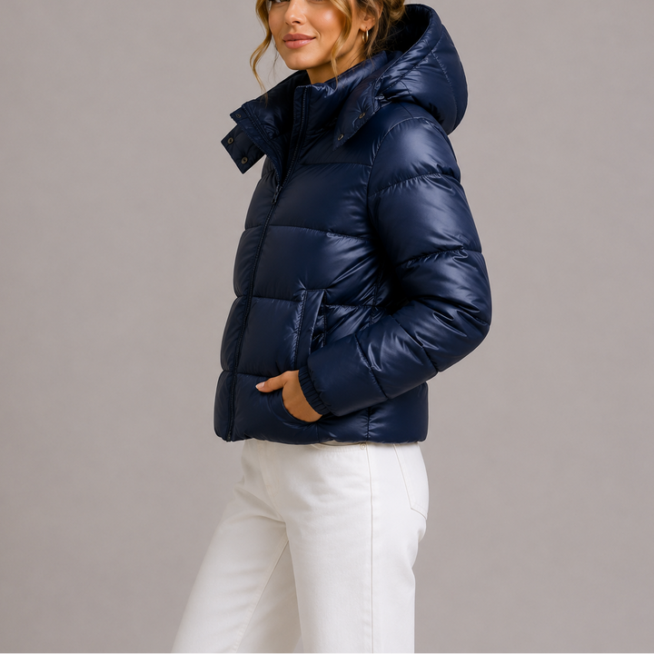 Woman wearing navy glossy hooded puffer jacket, side view