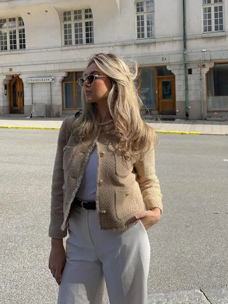 Woman wearing beige cropped tweed jacket with patch pockets and trousers