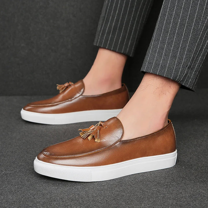 Man wearing brown tasseled leather loafer with white sole, side view