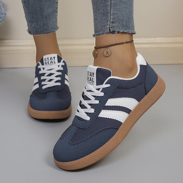 Navy blue sneaker front view with white stripes and gum sole