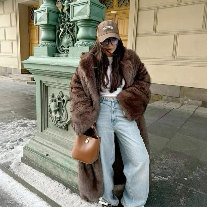 Woman in dark brown faux fur coat with wide sleeves standing outdoors