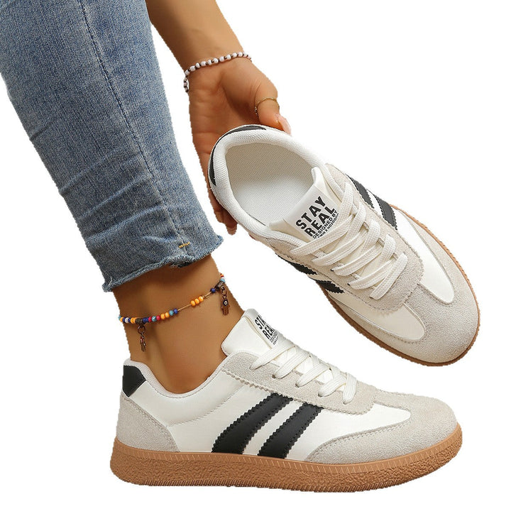 White and black sneaker held by hand showing interior and sole detail