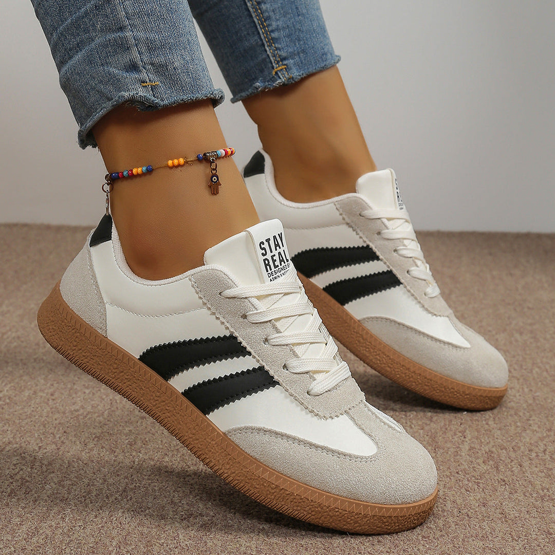 White sneaker with black side stripes and suede-look panels, worn on foot
