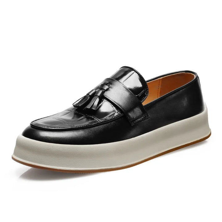 Black tasseled loafer with croc-embossed toe on white background