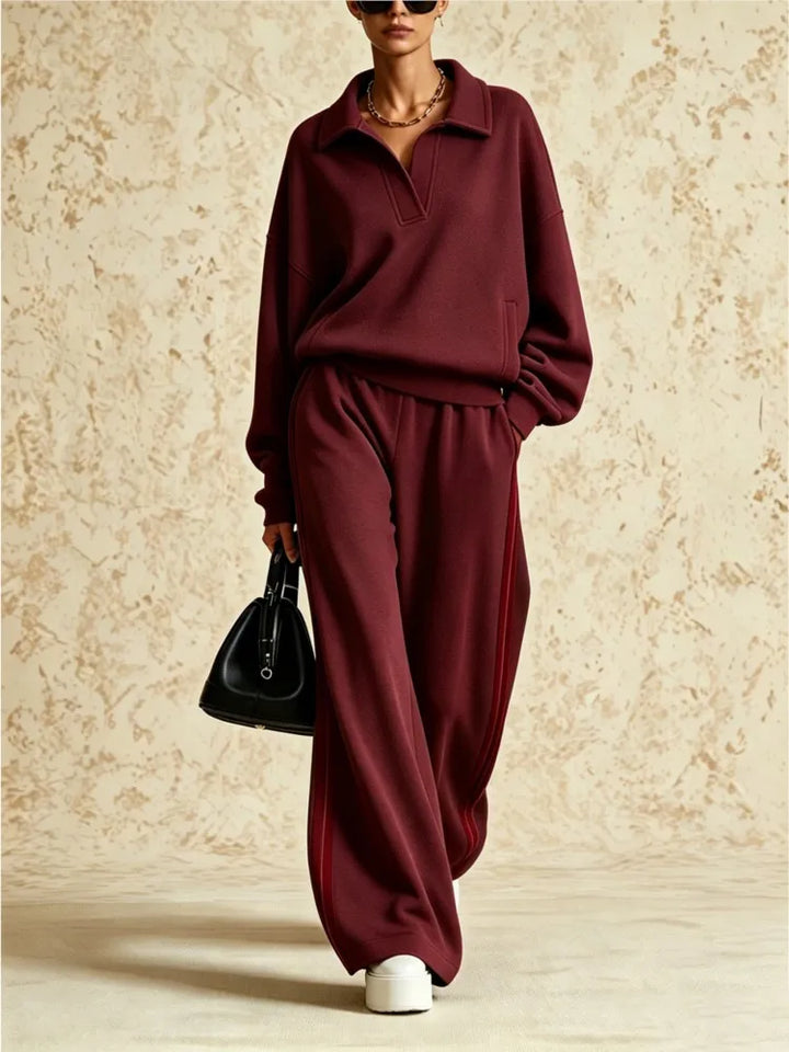 Woman wearing burgundy two piece collared sweatsuit with red side stripe pants