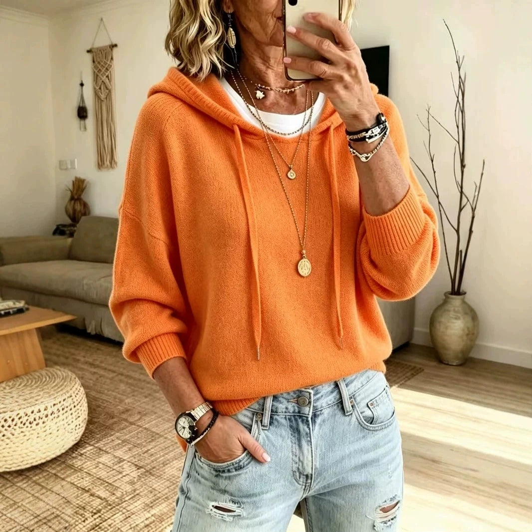 Woman wearing orange knit drawstring hoodie with jeans, front view