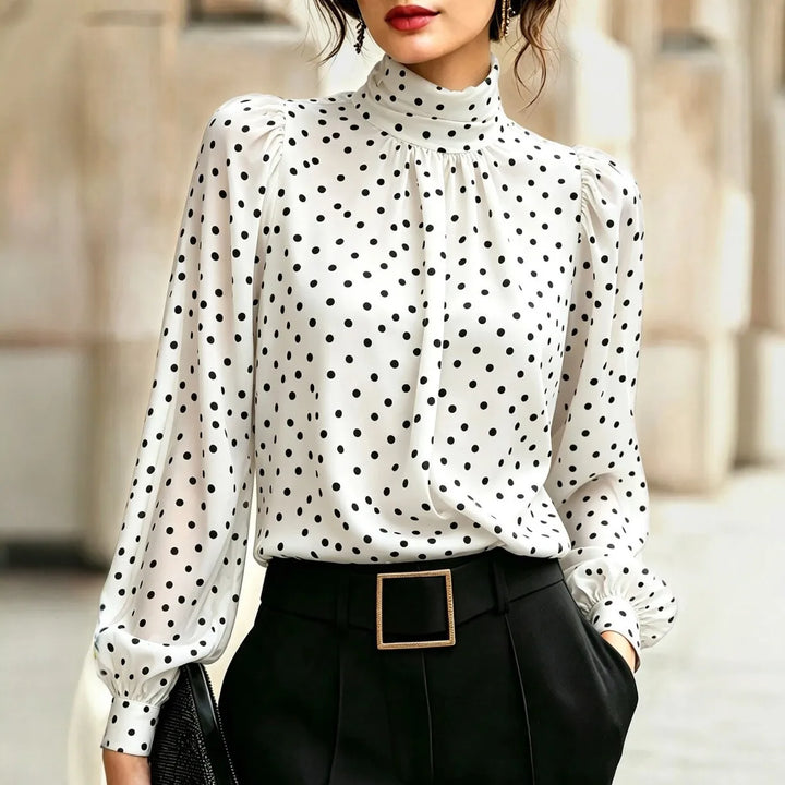Woman wearing white polka dot blouse with high mock neck and lantern sleeves