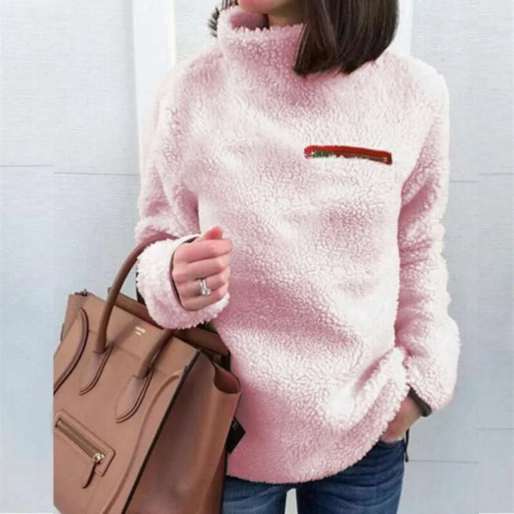 Woman wearing pink sherpa turtleneck pullover with zip chest pocket