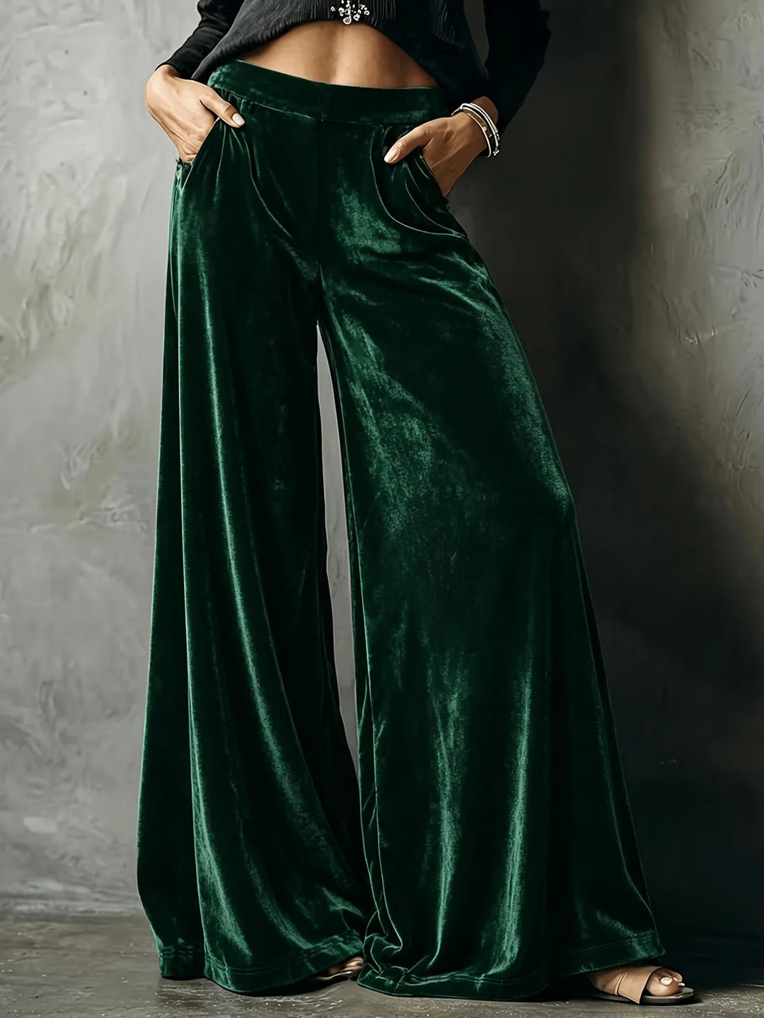 Woman wearing dark green velvet wide leg pants with hands in pockets