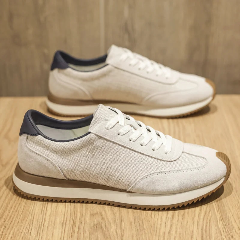Pair of white textured sneakers with navy heel tab on wood surface