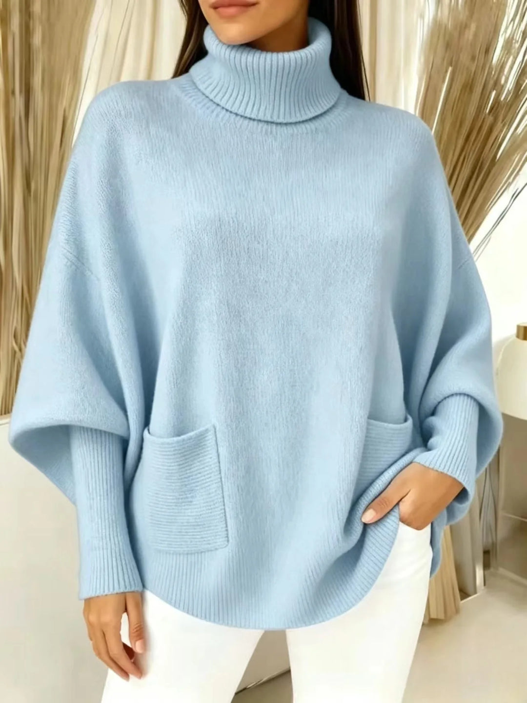 Woman wearing sky blue turtleneck batwing sweater with front pocket