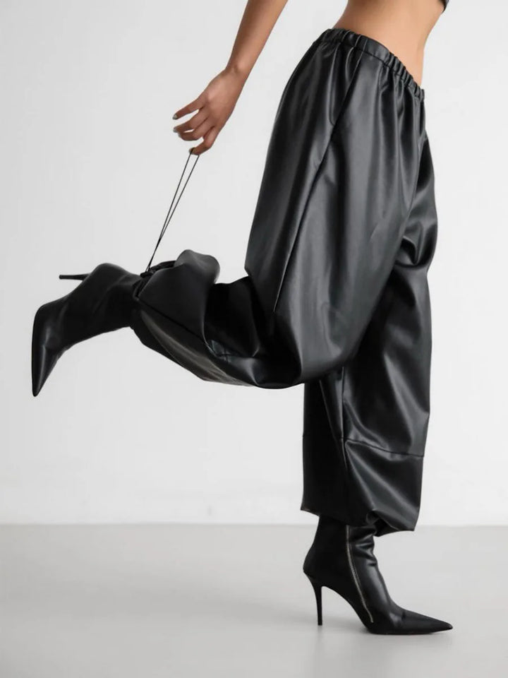 Side view of black faux leather lantern pants showing tapered cuff detail