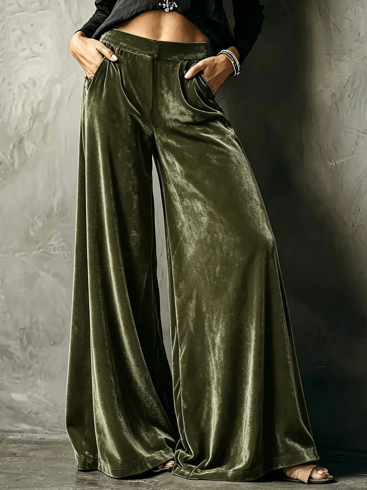 Woman wearing army green velvet wide leg pants with hands in pockets
