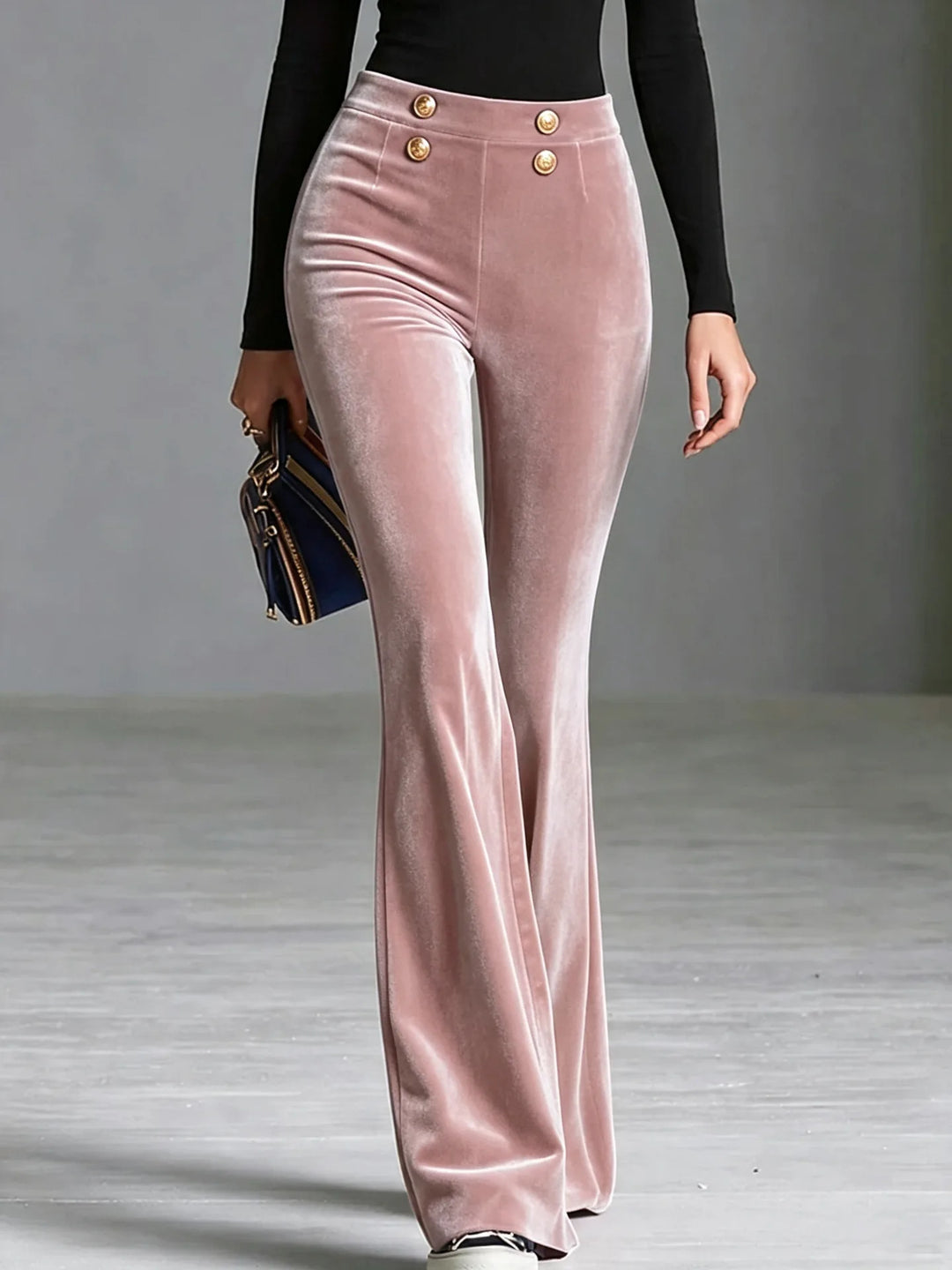 Woman wearing pink velvet flared high waist pants with gold buttons, close front view