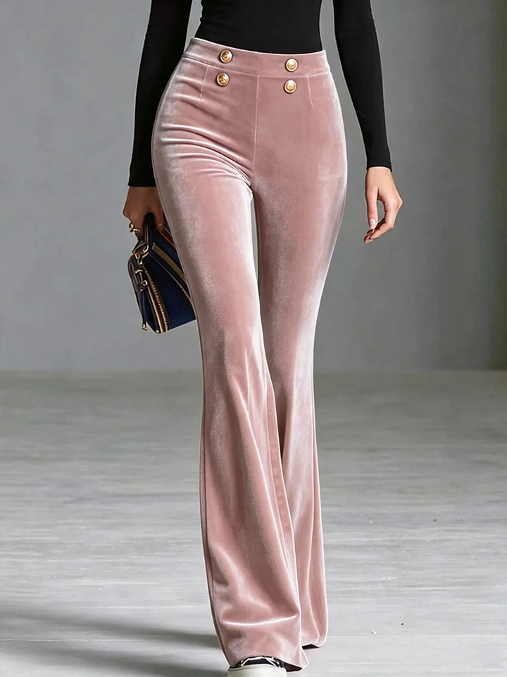 Woman wearing pink velvet flared high waist pants with gold buttons, close front view