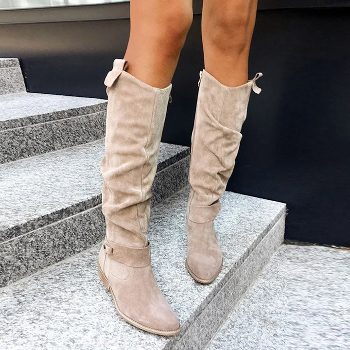 Apricot suede knee-high slouch boots with buckle strap, front view on stairs