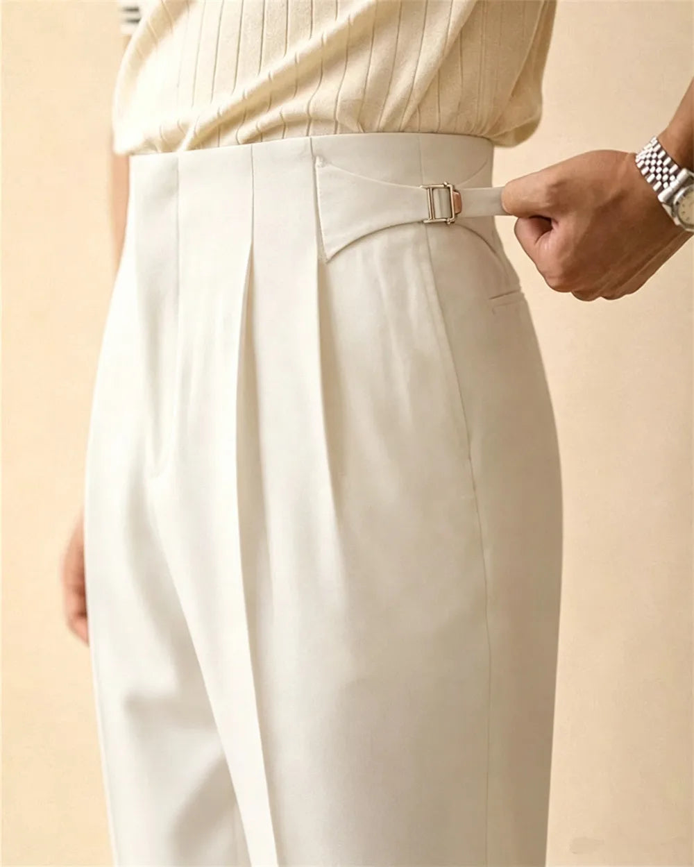 Close up of white pleated trousers with side buckle detail