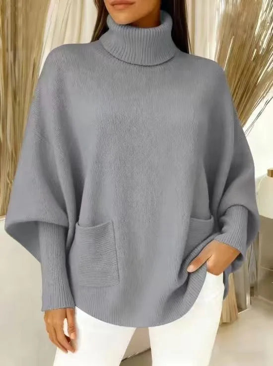 Woman wearing grey turtleneck batwing sweater with front pocket