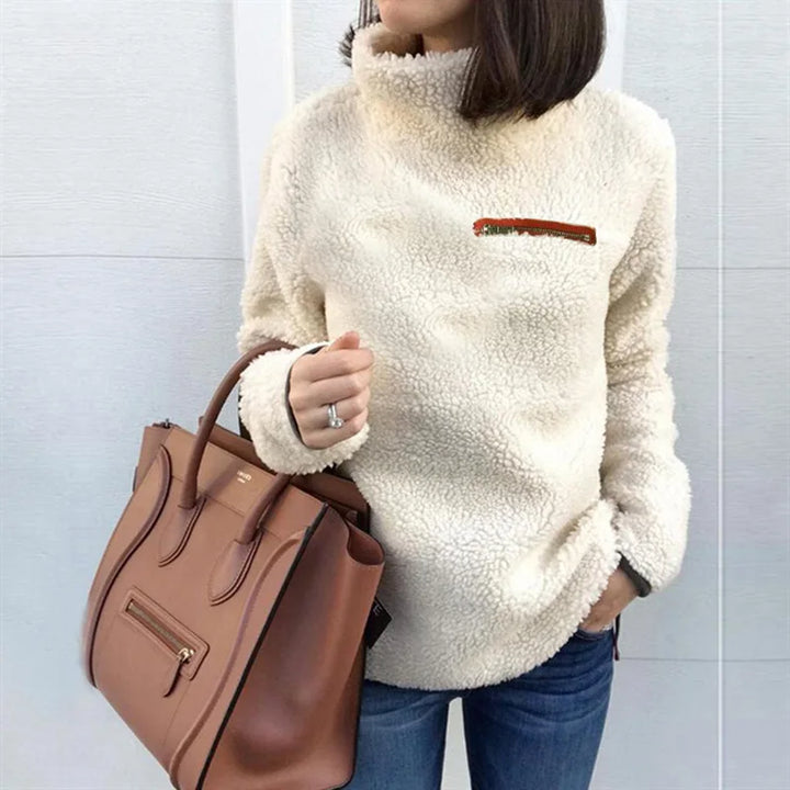 Woman wearing light apricot sherpa turtleneck pullover with zip chest pocket