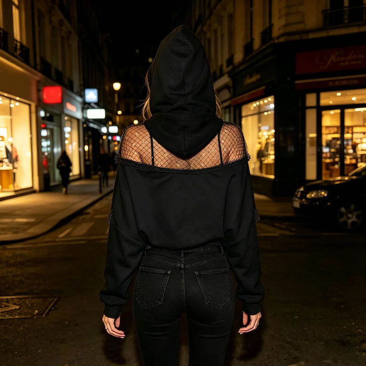 Woman wearing black cropped hoodie with fishnet shoulder panel, back view on city street