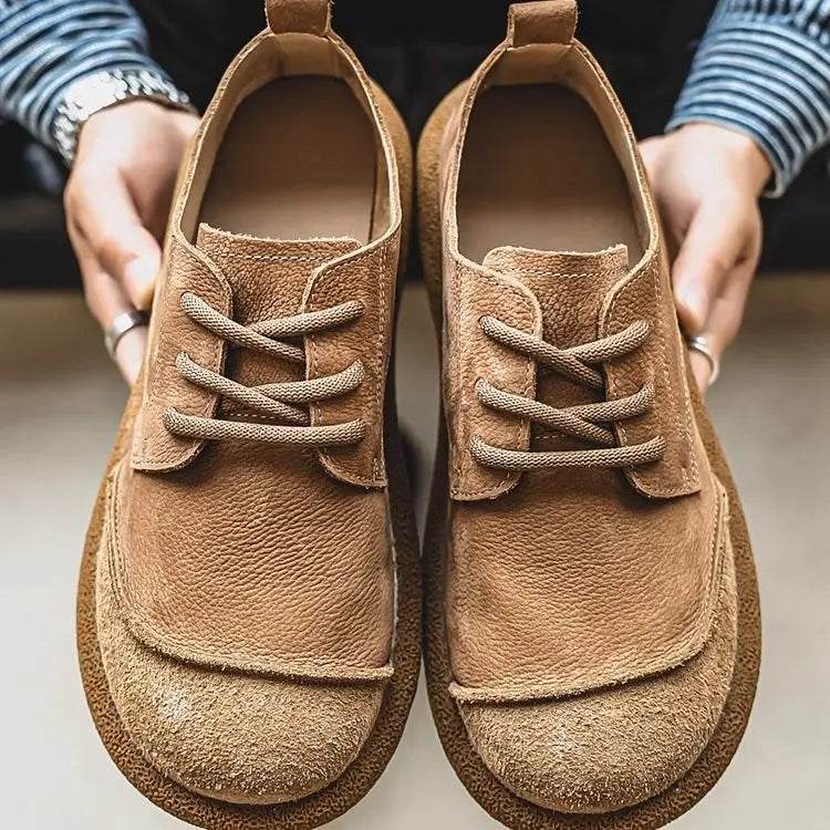 Khaki suede toe lace up shoes held in hands, front view