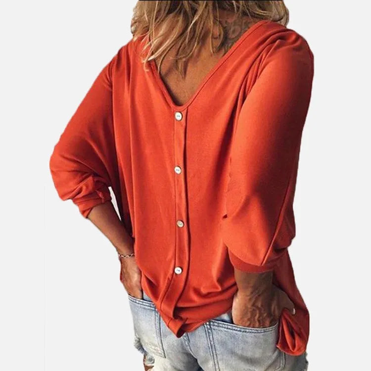 Woman wearing orange top with back button detail, close view