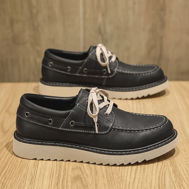 Black leather boat shoes side and front view on wood surface