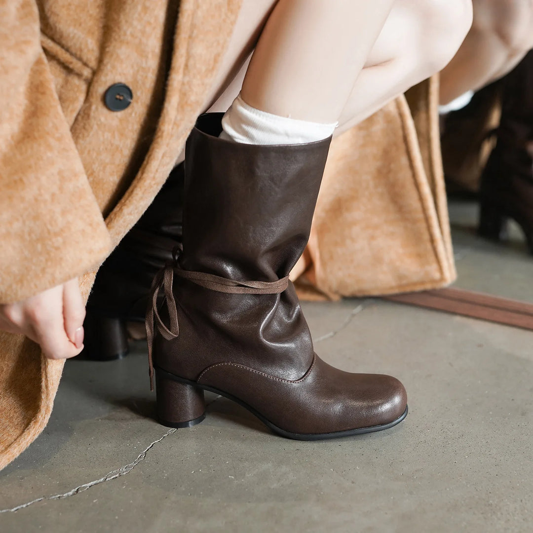 Model wearing brown mid-calf boot with ankle tie detail