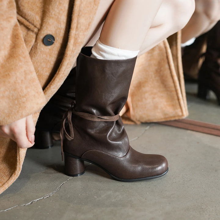Model wearing brown mid-calf boot with ankle tie detail