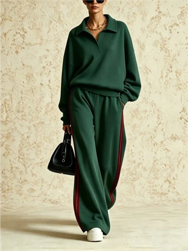 Woman wearing dark green two piece collared sweatsuit with red side stripe pants