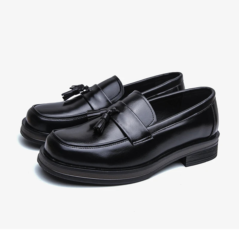 Pair of black tassel loafers on white background