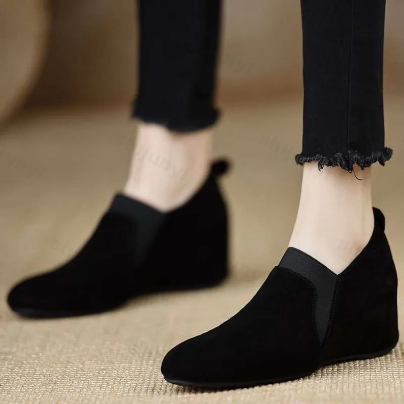 Black suede wedge booties on both feet walking view