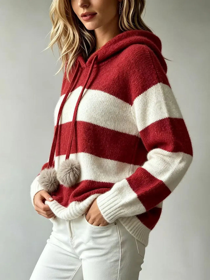 Side view of striped hooded knit sweater with pom pom drawstrings