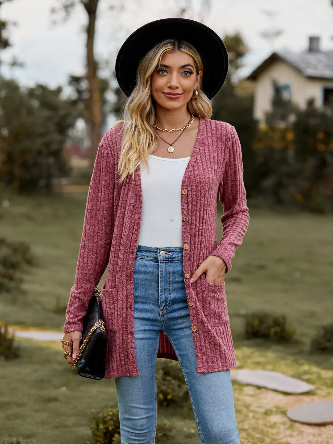 Woman in black hat wearing burgundy ribbed knit cardigan