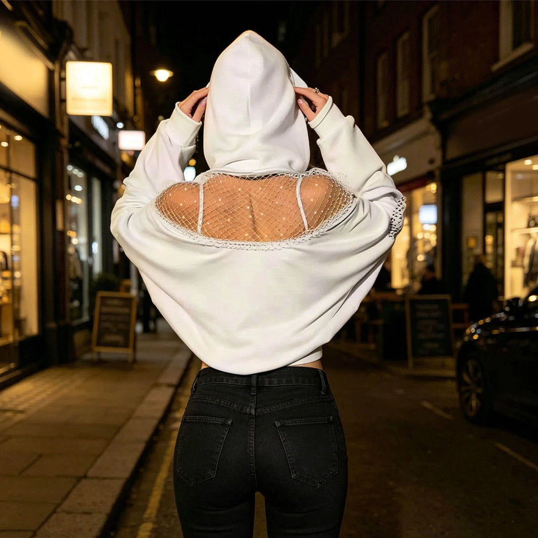 Woman wearing white cropped hoodie with fishnet shoulder panel, back view on city street