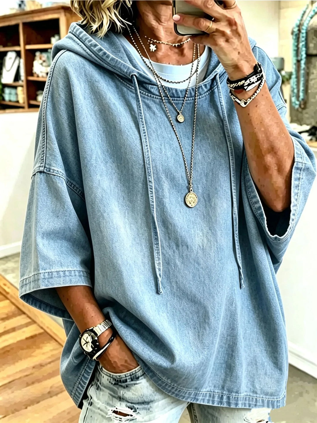 Close up of light blue denim hoodie with layered necklaces