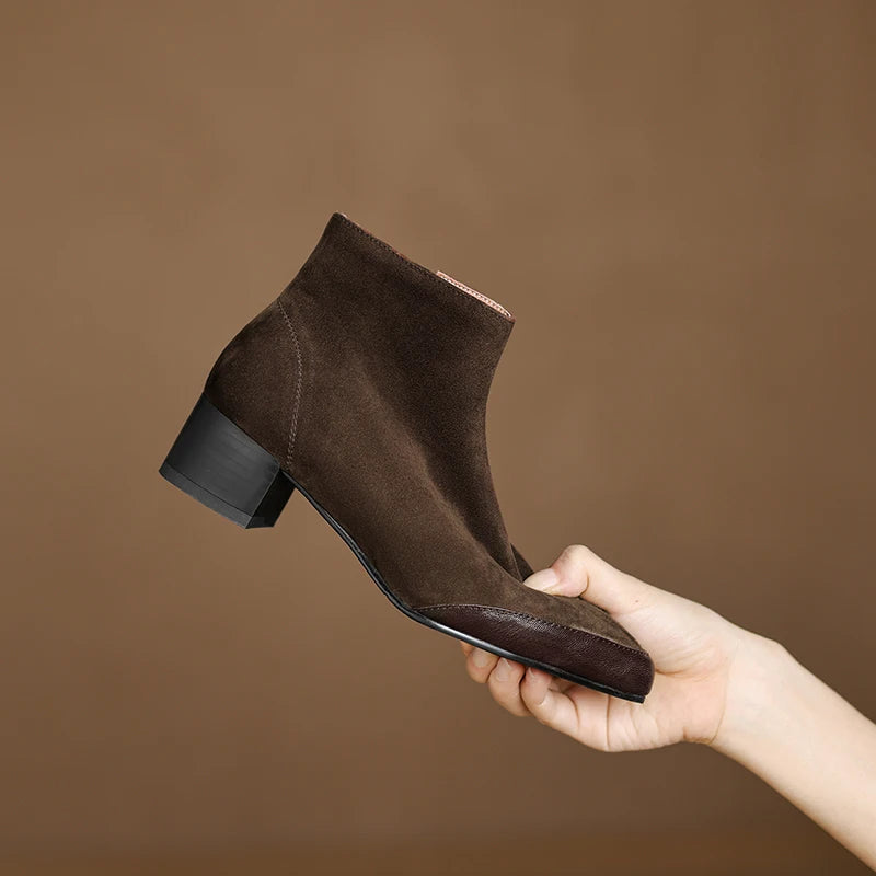 Brown suede ankle boot held in hand showing side profile