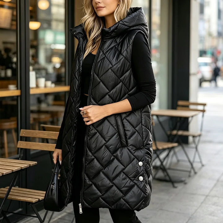 Woman wearing black diamond quilted long puffer vest with hood over black outfit