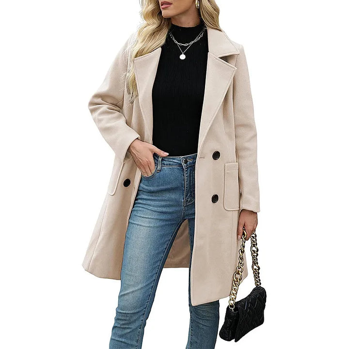 Woman wearing apricot double breasted wool coat with black turtleneck and jeans