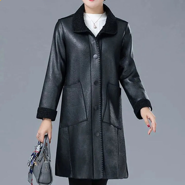 Woman wearing black faux leather longline jacket with shearling collar, front view