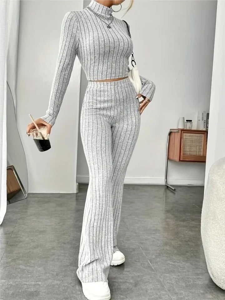 Woman wearing light grey ribbed knit crop top and flare pants set, front view
