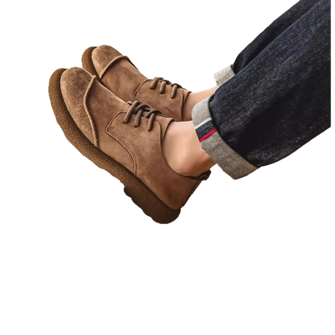 Khaki lace up shoes worn on feet with cuffed denim