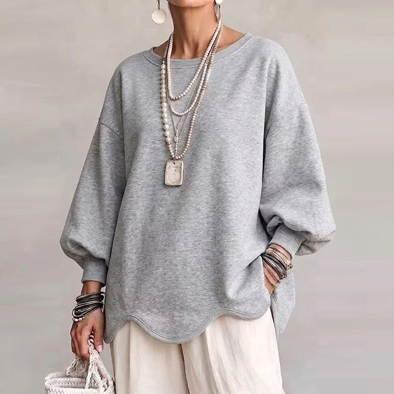 Woman wearing light gray oversized sweatshirt with wavy hem